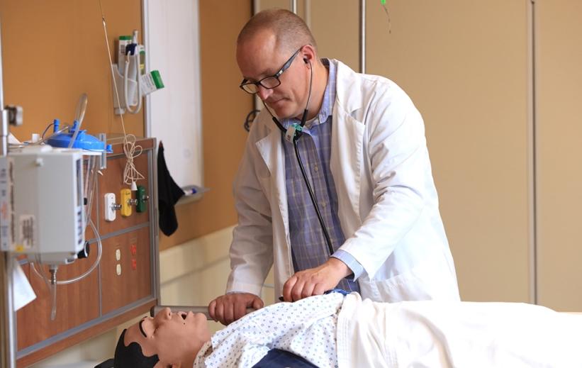 A nurse in a white coat practices in vnsr威尼斯城官网登入's nursing simulation center.